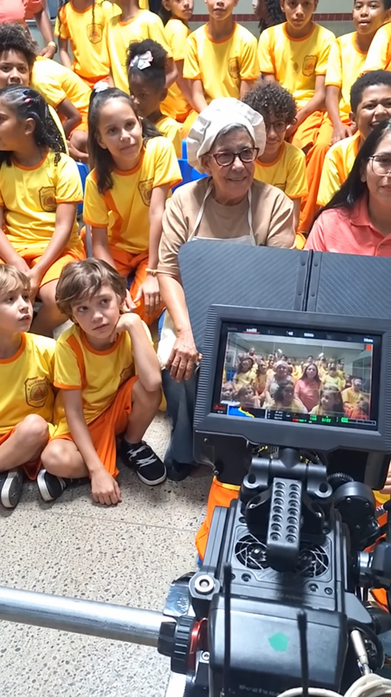 Bastidores de uma filmagem, com um grupo diante da câmera e do monitor