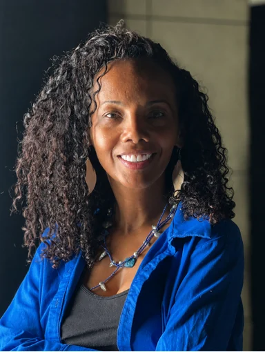 Retrato de Simone Borges, sorrindo e vestindo uma camisa azul