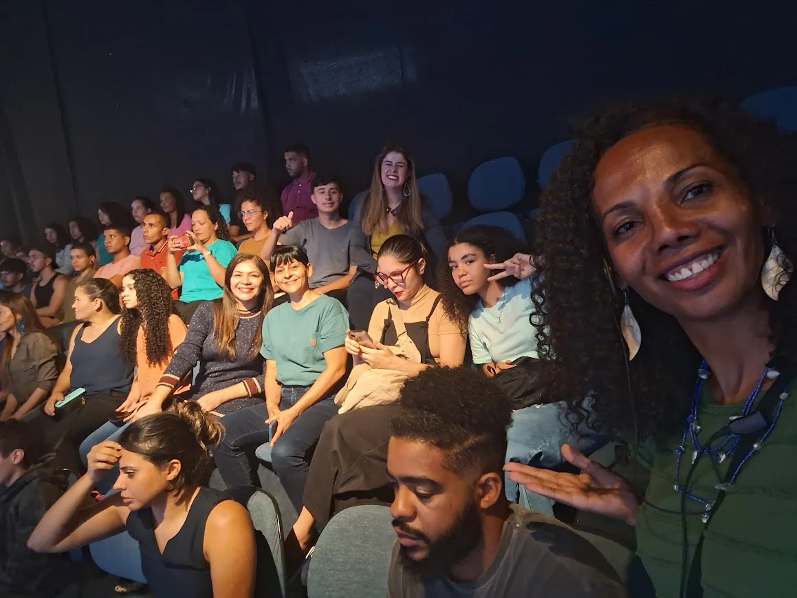 Simone Borges em uma selfie com a plateia de um auditório ao fundo